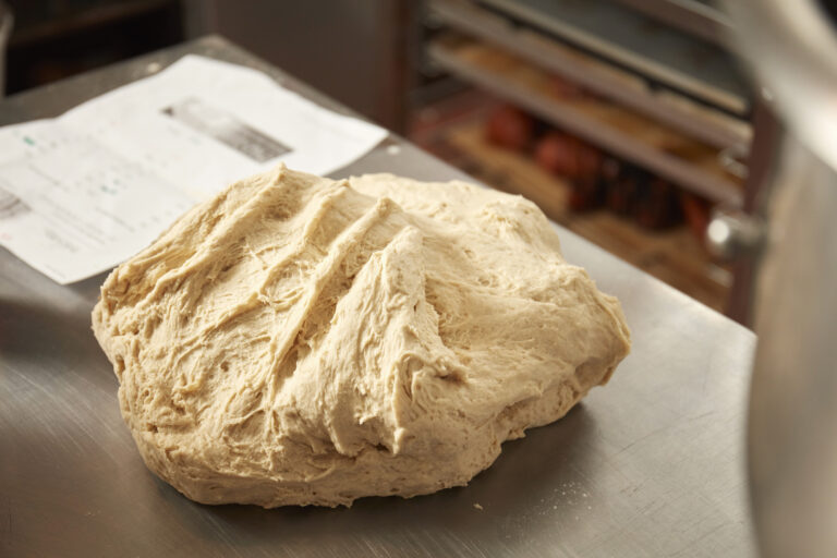 A lump of dough shaped and resting on a work surface.