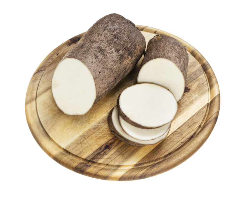sliced tuber of african yam on wooden cutting board isolated on white background